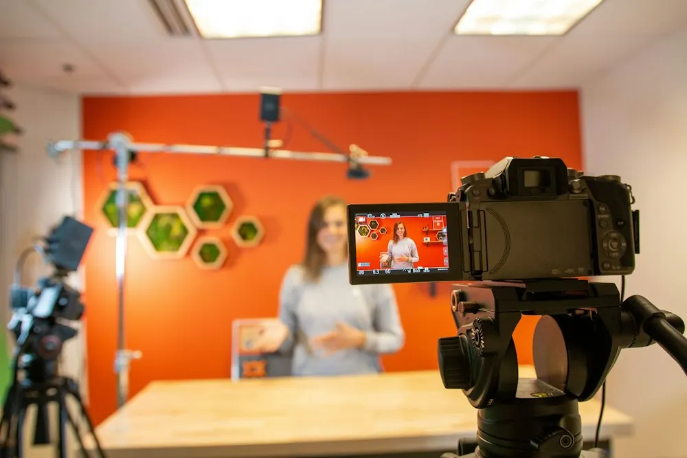 Animatrice présentant un produit face caméra, retour vidéo au premier plan